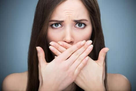Une femme qui se cache la bouche avec les deux mains. 
