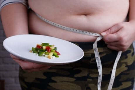 Un ventre obèse devant une assiette minceur. 