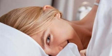 Une femme qui sourit dans son lit. 