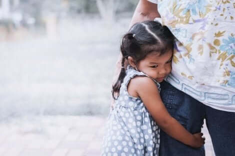 Une jeune fille qui s'accroche aux jambes de son papa. 