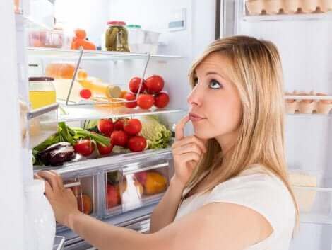Une femme devant son réfrigérateur.