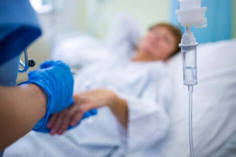Une femme sous perfusion dans un lit d'hôpital. 