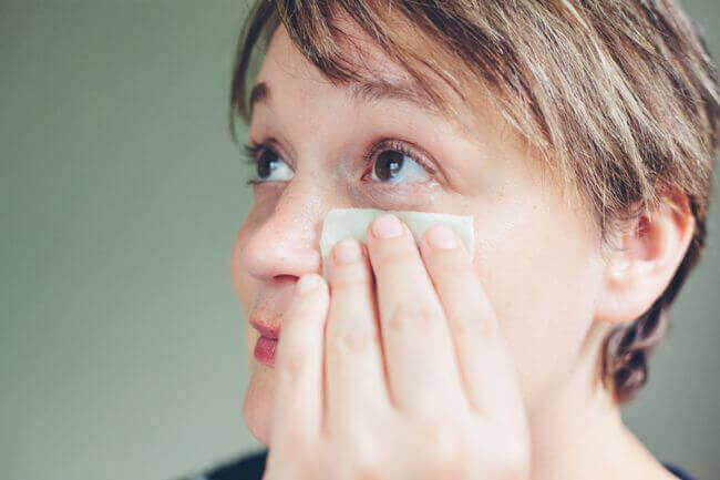 Une femme nettoyant ses paupières.