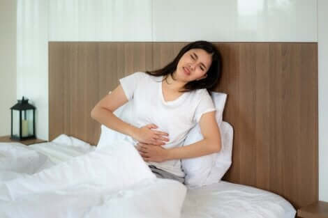 Une femme au lit qui souffre de douleurs abdominales. 