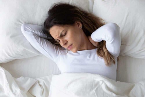 Une femme dans son lit souffrant de douleurs à la nuque.