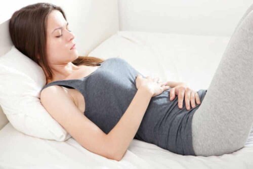 Une femme allongée souffrant de maux de ventre. 