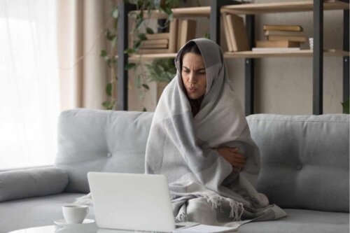 Une femme qui a froid dans son salon.