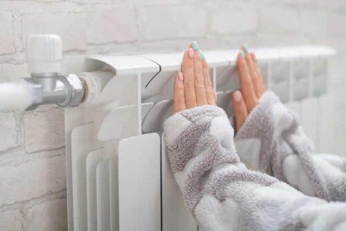 Une femme qui pose ses mains sur un radiateur. 