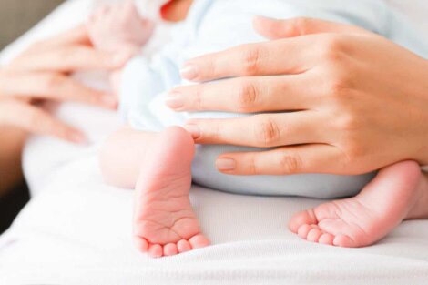 Une maman qui tient son bébé dans ses bras.
