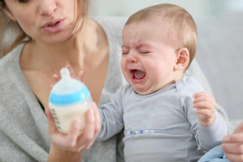 Un bébé qui pleure devant son biberon.