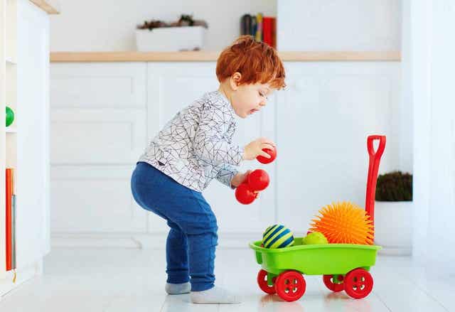 Un enfant rangeant ses jouets.
