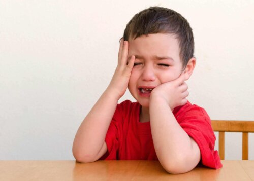 Un enfant qui pleure en se touchant la tête. 