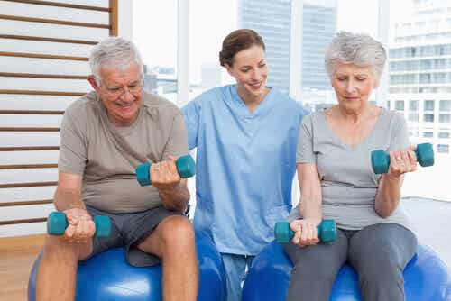 Deux personnes âgées qui font de l'exercice avec une soignante. 
